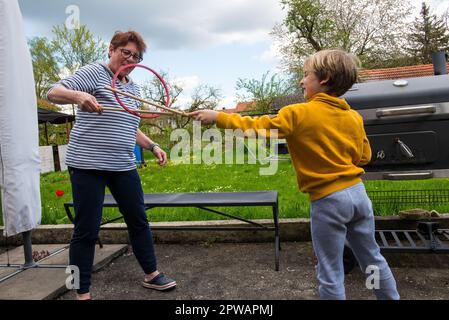 Una donna di mezza età gioca con suo nipote nel cortile Foto Stock