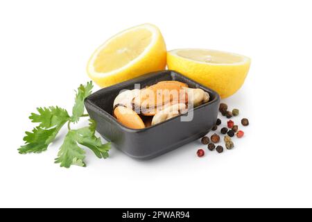 Cozze marinate in ciotola quadrata con metà limone, prezzemolo e pepe di mais su fondo bianco Foto Stock
