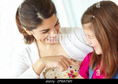 Ha le sue madri sorridere. Una giovane madre che stuzzica affettuosamente la figlia mentre si siede sul portico. Foto Stock