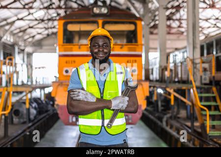 Ritratto Africano nero lavoro maschile in locomotiva riparazione Negozi in piedi felice sorridendo con la chiave Foto Stock