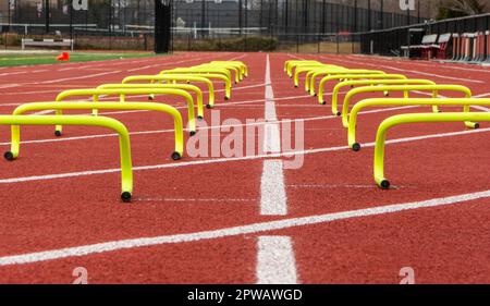 Primo piano vista ad angolo basso di piccoli ostacoli a banana gialli allestiti in due corsie su una pista per consentire ai corridori di correre in pista e sul campo. Foto Stock