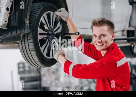 ritratto happy meccanico operatore garage godere di servizio auto. sostituzione degli pneumatici in officina auto. Foto Stock