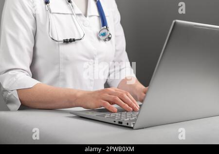 Medico che lavora al computer portatile, utilizzando le tecnologie dell'informazione e l'intelligenza artificiale. Foto Stock