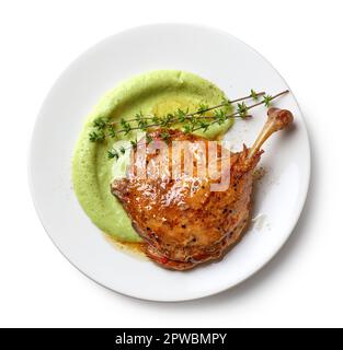 piatto di confit gamba d'anatra e purea di broccoli isolato su sfondo bianco, vista dall'alto Foto Stock