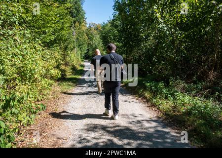 Zwei Männer laufen auf einem Weg im Wald hintereinander lei Foto Stock