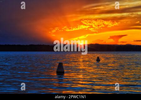 Tramonto del sole che tocca l'orizzonte al Lago Macquarie in Australia. Foto Stock