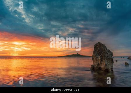 Il sole tramonta dietro l'isolotto di Isola delle femmine, in Sicilia Foto Stock