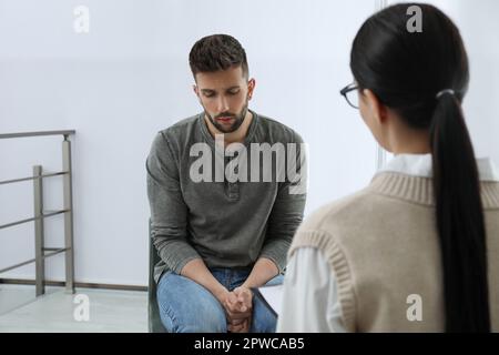 Psicoterapeuta che lavora con l'uomo tossicodipendente al chiuso Foto Stock