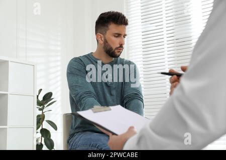 Psicoterapeuta che lavora con l'uomo tossicodipendente al chiuso Foto Stock