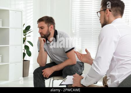 Psicoterapeuta che lavora con un giovane tossicodipendente al chiuso Foto Stock