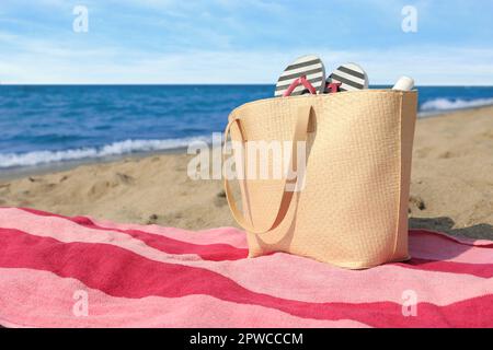 Asciugamano a strisce rosa con borsa e infradito in spiaggia Foto Stock