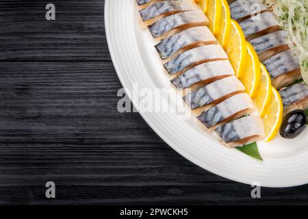 Filetti di aringa con cipolla e fettine di limone su vecchio tavolo rustico Foto Stock