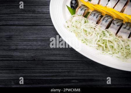 Filetti di aringa con cipolla e fettine di limone su vecchio tavolo rustico Foto Stock