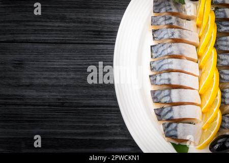 Filetti di aringa con cipolla e fettine di limone su vecchio tavolo rustico Foto Stock