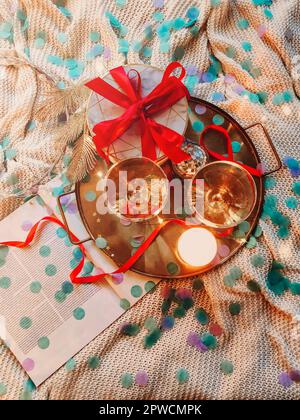 Vassoio con decorazioni e scatola regalo posta su comodo letto in camera da letto accogliente decorato per Natale celebrazione di notte Foto Stock