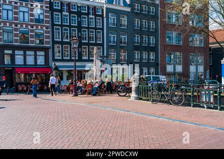 AMSTERDAM, OLANDA - 17 APRILE 2023: Vista sulla strada di Amsterdam, capitale olandese conosciuta per il suo elaborato sistema di canali, case strette e ciclismo Foto Stock