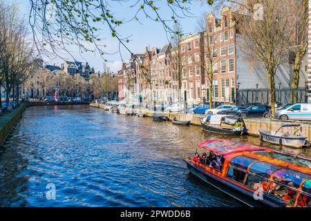 AMSTERDAM, OLANDA - 17 APRILE 2023: I Toursts Godetevi una gita in barca lungo un canale ad Amsterdam, capitale dei Paesi Bassi Foto Stock