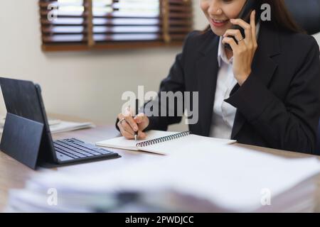 Secretary Concept, segretaria femminile che parla al telefono con il dirigente e prende appunti in taccuino. Foto Stock