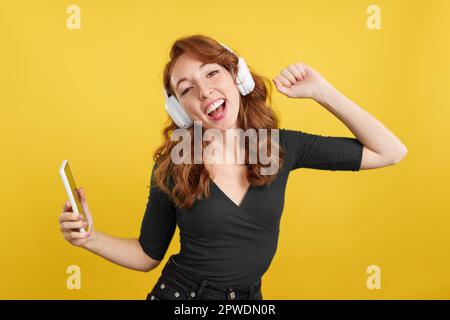 Donna felice rossa che ascolta musica e danza Foto Stock
