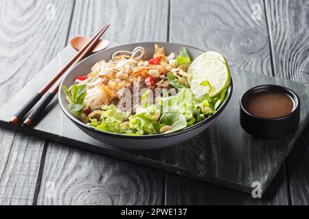 Pho Bo Tron insalata di manzo vietnamita spaghetti di riso primo piano in una ciotola su un tavolo di legno. orizzontale Foto Stock
