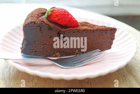 Primo piano di tessuto umido e denso di saporito torta al cioccolato senza farina ricoperta di fragola fresca Foto Stock