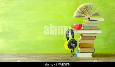 concetto di audiolibro con stack di libri, uno aperto, caffè e cuffie vintage, panoramico, spazio copia gratuito Foto Stock