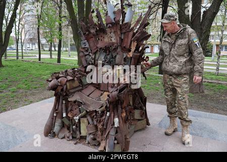 Il soldato dell'esercito ucraino è visto guardando il Trono di ferro dell'Oriente nel centro di Zaporizhzhia. Il Trono di ferro dell'Est a Zaporizhzhzhia, Ucraina, fatto di veri e propri macchinari militari, relitti e conchiglie. Fu fatto nelle posizioni delle forze armate dell'Ucraina nella città di Avdiivka nella regione di Donetsk nell'inverno del 2016. Il Trono di ferro dell'Est è stato installato nella città di Zaporizhzhia con il sostegno dei deputati locali - veterani di guerra. Onora l'eccezionale volontà del popolo ucraino di vincere. Gli autori di questa scultura metallica sono stati ispirati dal famoso dramma fantasy Game of Foto Stock