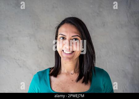 Ritratto di felice donna nordafricana - fiduciosa e sorridente giovane donna marocchina con capelli lisci e denti peculiari che si divertono mentre si posa davanti Foto Stock