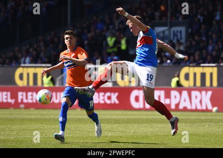 30 aprile 2023, Schleswig-Holstein, Kiel: Calcio: 2nd Bundesliga, Holstein Kiel - Darmstadt 98, Giornata 30, Stadio Holstein. Simon Lorenz (r) di Kiel gioca la palla prima che Mathias Honsak di Darmstadt possa avvicinarsi. Foto: Gregor Fischer/dpa - NOTA IMPORTANTE: Conformemente ai requisiti della DFL Deutsche Fußball Liga e della DFB Deutscher Fußball-Bund, è vietato utilizzare o utilizzare fotografie scattate nello stadio e/o della partita sotto forma di sequenze di immagini e/o serie di foto simili a un video. Foto Stock