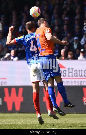 30 aprile 2023, Schleswig-Holstein, Kiel: Calcio: 2nd Bundesliga, Holstein Kiel - Darmstadt 98, Giornata 30, Stadio Holstein. Christoph Zimmermann (r) di Darmstadt e Patrick Erras di Kiel combattono per la palla in aria. Foto: Gregor Fischer/dpa - NOTA IMPORTANTE: Conformemente ai requisiti della DFL Deutsche Fußball Liga e della DFB Deutscher Fußball-Bund, è vietato utilizzare o utilizzare fotografie scattate nello stadio e/o della partita sotto forma di sequenze di immagini e/o serie di foto simili a un video. Foto Stock