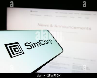 Telefono cellulare con il logo della società danese di software finanziario SimCorp COME su schermo di fronte al sito web aziendale. Messa a fuoco al centro del display del telefono. Foto Stock