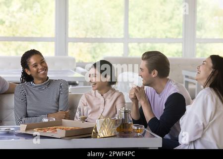 Un gruppo di amici diversi si diverti a parlare, a trascorrere del tempo in pizzeria Foto Stock