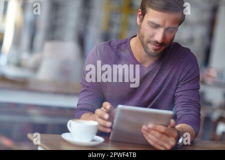 Dare a questa caffetteria una buona recensione. un bel giovane uomo che usa il suo tablet in una caffetteria. Foto Stock