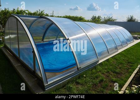 Piscina all'aperto con coperchio scorrevole. Protezione contro le intemperie Foto Stock