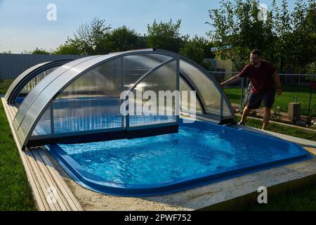 Piscina all'aperto con coperchio scorrevole. Protezione contro le intemperie Foto Stock