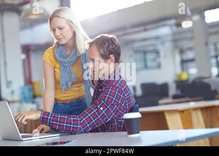 Theyve ha ottenuto la tecnologia dal loro lato. due designer che lavorano su un notebook in ufficio. Foto Stock