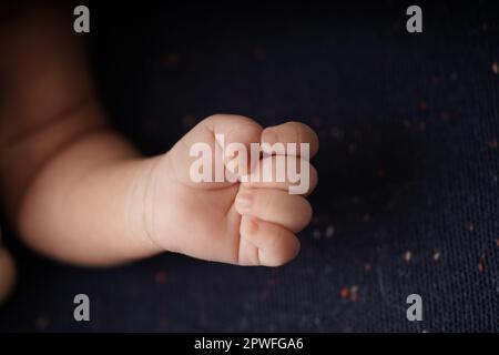 Piccolo bambino mani su coperta di sfondo blu navy. vista ravvicinata della mano carina del bambino il bambino sta comodamente adagiando in una coperta blu. Foto Stock