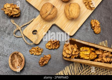 Nocciola in legno e su tavola. Dadi interi a bordo. Giacitura piatta. Sfondo marrone. Foto Stock