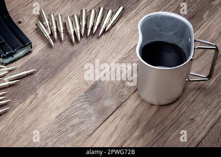 Cartucce e caffè nero. Fucili d'assalto cartucce e tazza di caffè su sfondo tavolo di legno. Foto Stock