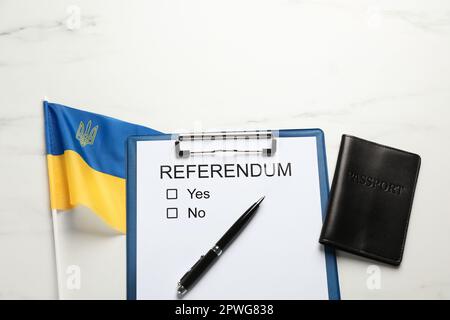 Referendum con passaporto, penna e bandiera dell'Ucraina su tavola di marmo bianco, piatto Foto Stock