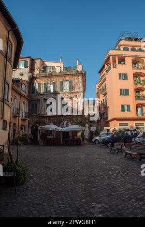 Roma, vista su una tranquilla piazza residenziale sul Lungotevere, con appartamenti, balconi, auto e biciclette parcheggiate, bar e ristorante all'aperto Foto Stock