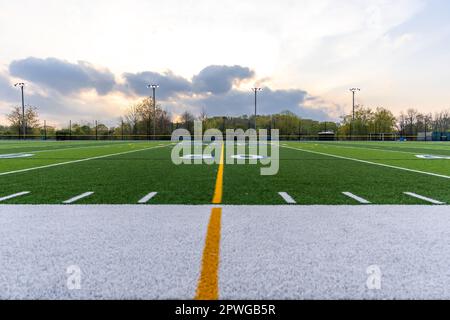 Foto drammatica nel tardo pomeriggio della linea di 50 iarde su un campo da calcio sintetico in erba sintetica. Foto Stock