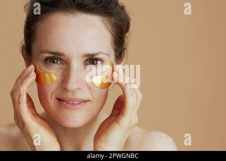 Ritratto di donna di mezza età con macchie sull'occhio su sfondo beige. Foto Stock