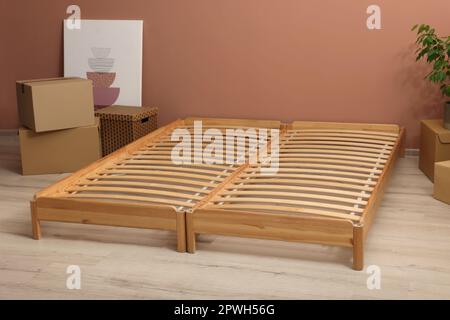 Struttura del letto in legno e scatole di cartone sul pavimento in camera Foto Stock