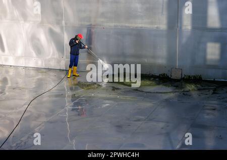 26 aprile 2023, Baviera, Norimberga: Michael, supervisore del turno e capocannone principale di Stadionbad, utilizza un sistema di lavaggio a pressione per rimuovere i detriti dovuti alle intemperie, come le alghe o le foglie, dalla piscina di immersione vuota di Stadionbad durante i lavori di pulizia in preparazione alla stagione delle piscine all'aperto 2023. A seconda del tempo, le prime piscine all'aperto sono previste per l'apertura all'inizio di maggio, mentre altre seguono l'esempio a metà mese, secondo diverse città bavaresi e operatori comunali di piscine. I prezzi di ammissione rimangono stabili in molti luoghi, ma molti operatori del pool si lamentano della carenza di personale Foto Stock