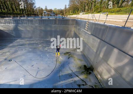 26 aprile 2023, Baviera, Norimberga: Michael, supervisore del turno e capocannone principale di Stadionbad, utilizza un sistema di lavaggio a pressione per rimuovere i detriti dovuti alle intemperie, come le alghe o le foglie, dalla piscina di immersione vuota di Stadionbad durante i lavori di pulizia in preparazione alla stagione delle piscine all'aperto 2023. A seconda del tempo, le prime piscine all'aperto sono previste per l'apertura all'inizio di maggio, mentre altre seguono l'esempio a metà mese, secondo diverse città bavaresi e operatori comunali di piscine. I prezzi di ammissione rimangono stabili in molti luoghi, ma molti operatori del pool si lamentano della carenza di personale Foto Stock