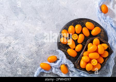Kumquat fresco maturo su un vecchio asse di legno. Vista dall'alto sulla frutta matura. Foto Stock