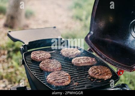 Delizioso hamburger di carne di manzo friggendo sul primo piano della griglia Foto Stock