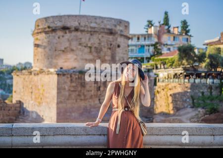 Donna turistica sullo sfondo della Torre Hidirlik di Antalya sullo sfondo della baia mediterranea dell'antico quartiere di Kaleici, Turchia Foto Stock