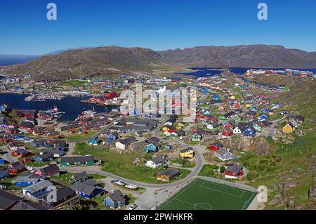 Vista su una piccola città, campo da calcio, aspro paesaggio montano, Qaqortoq, comune di Kujalleq, Artico, Groenlandia, Danimarca Foto Stock